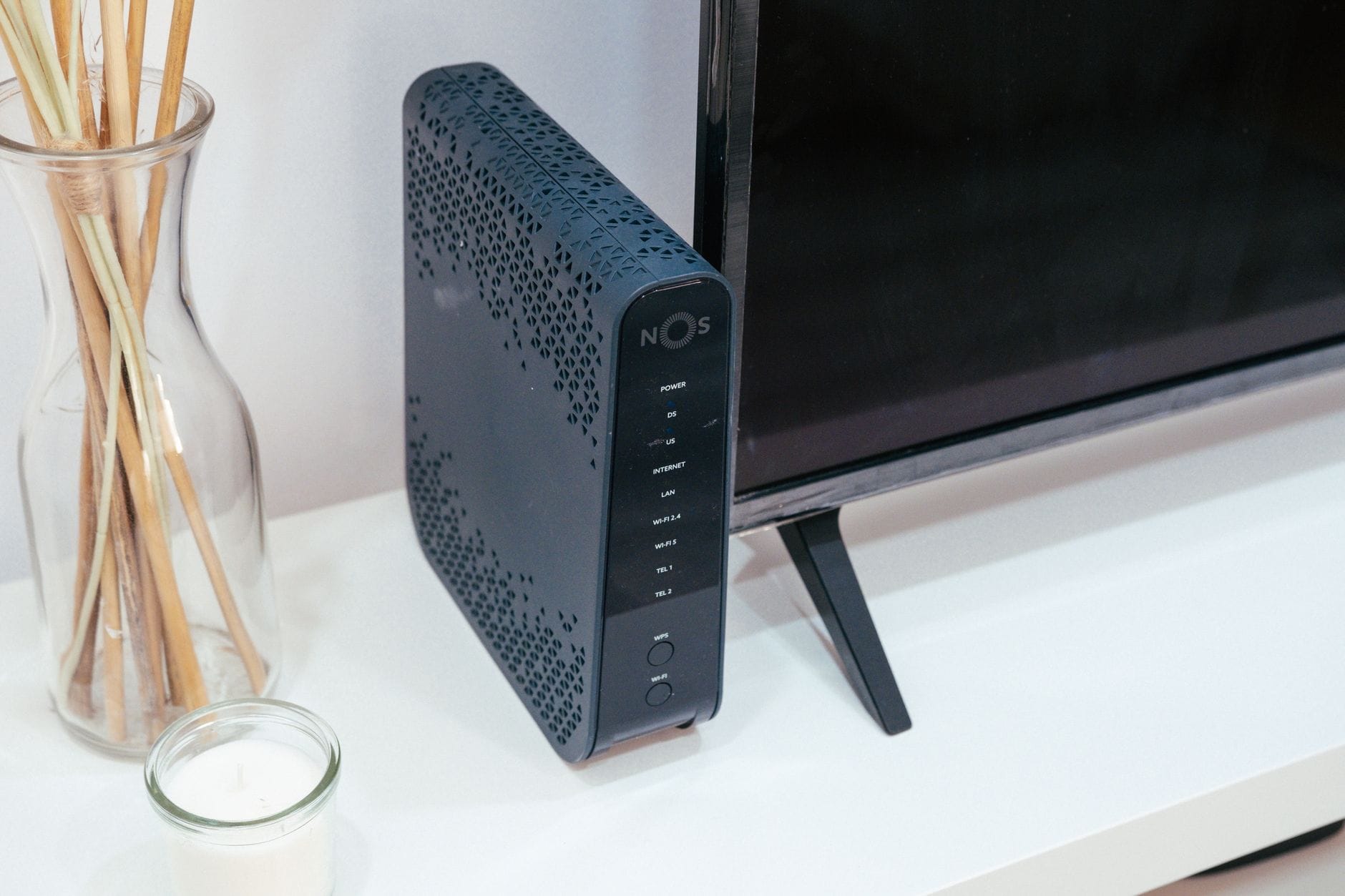 Nowoczesny router w domowym salonie obok telewizora i dekoracji